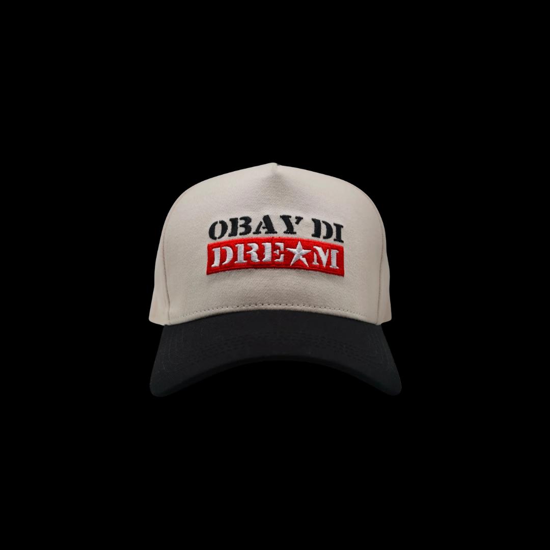 Front view of black OBAY DI DREAM trucker hat with snapback and white embroidered logo on front.