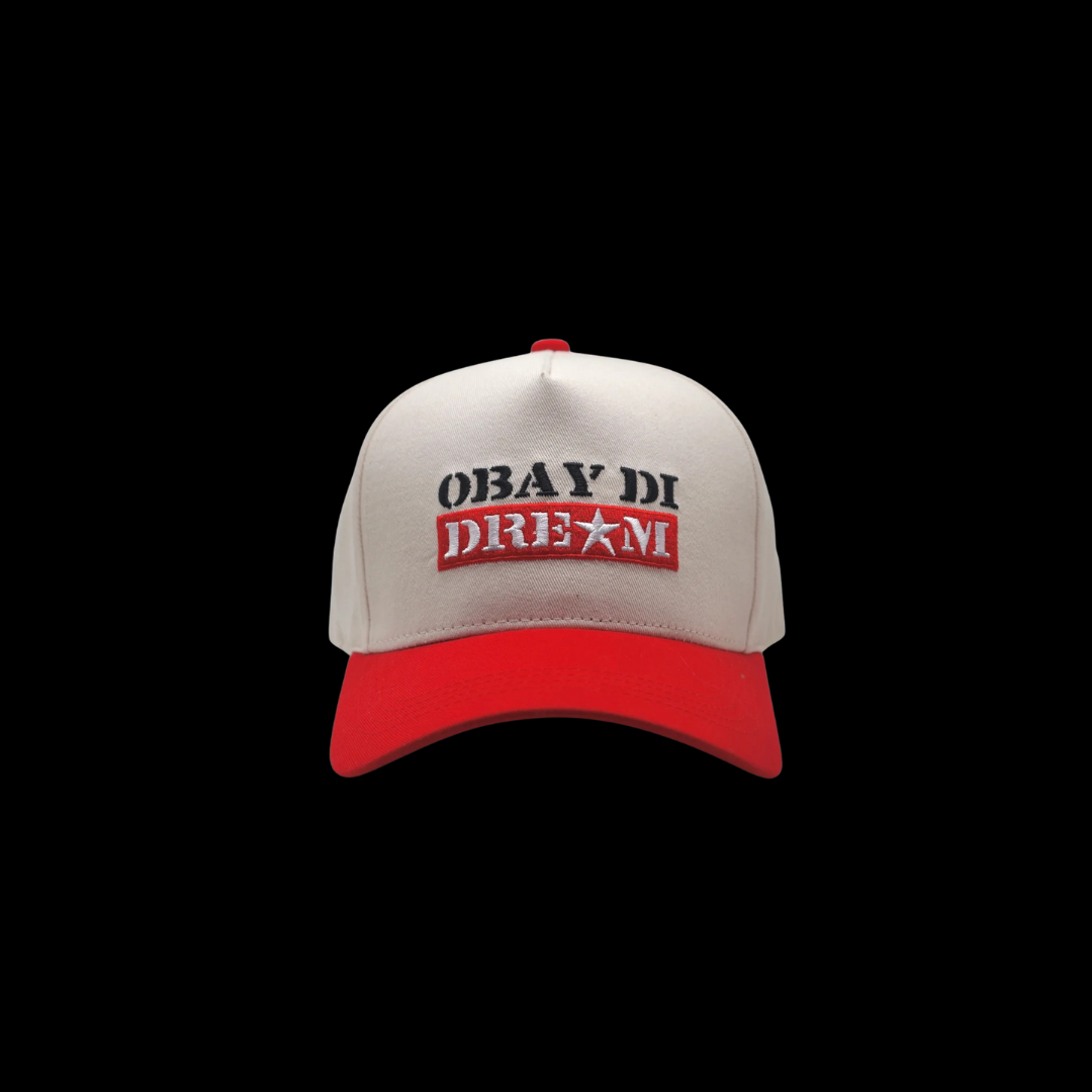 Front view of red OBAY DI DREAM trucker hat with snap closure  back and bold embroidery logo on structured front panel.