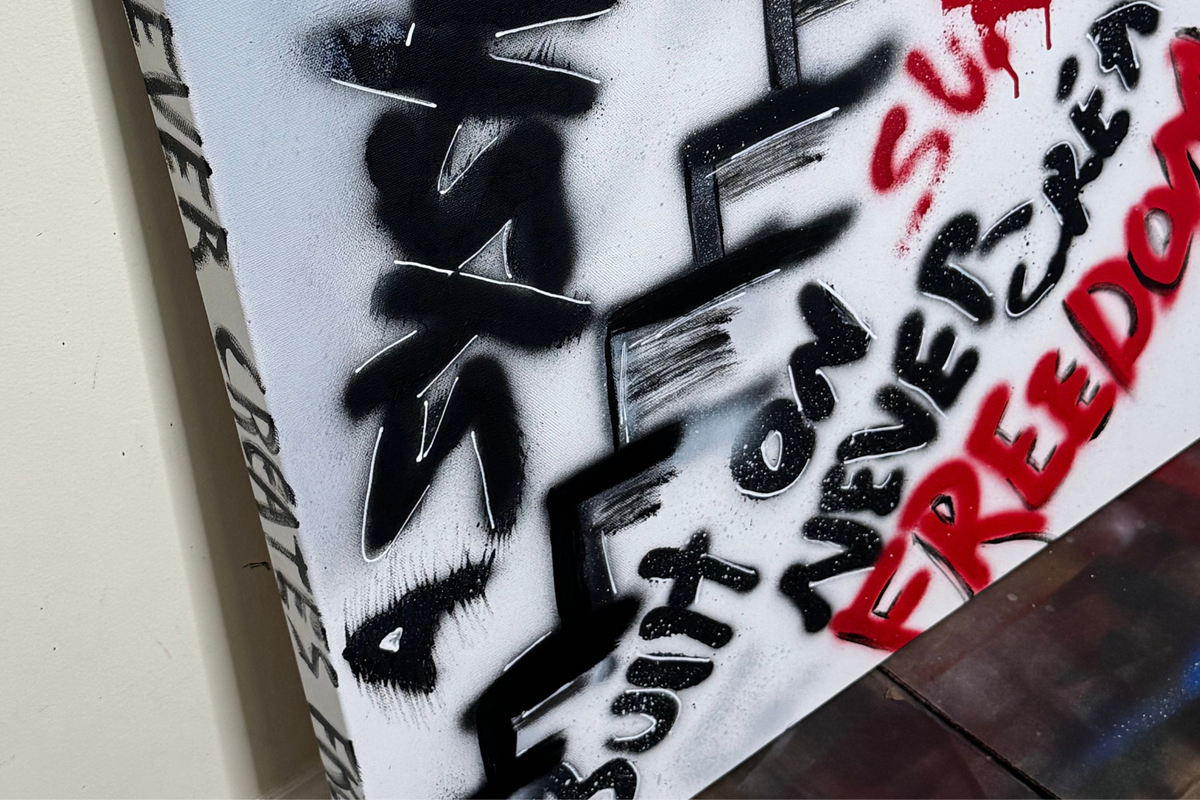 Close-up of OBAY DI DREAM's "A System Built on Survival Never Creates Freedom," showing layered spray-paint texture, white hand-drawn outlines, red drips, and the hand-lettered side edge.