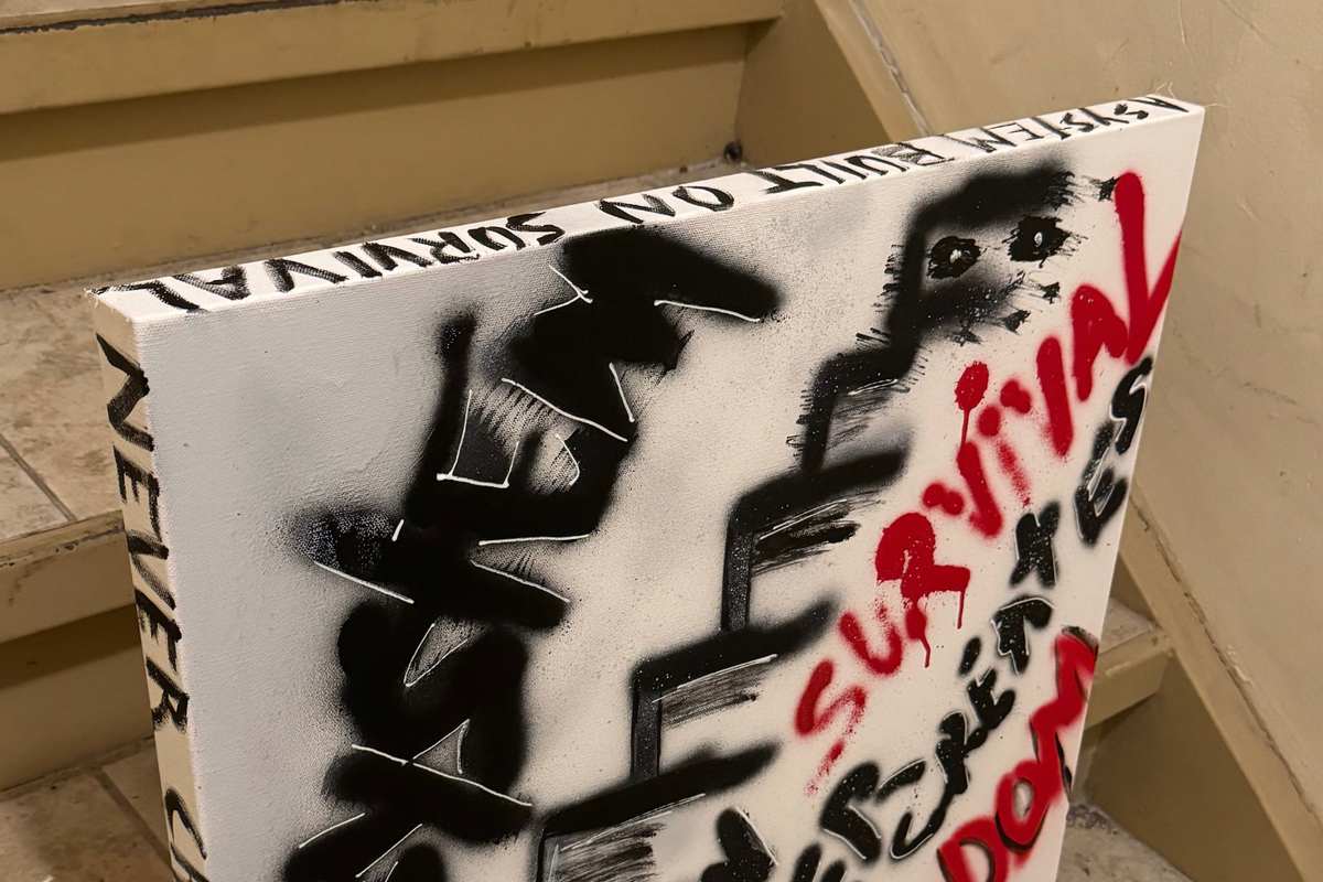 Close-up of OBAY DI DREAM's "A System Built on Survival Never Creates Freedom," showing layered spray-paint texture, white hand-drawn outlines, red drips, and the hand-lettered side edge.